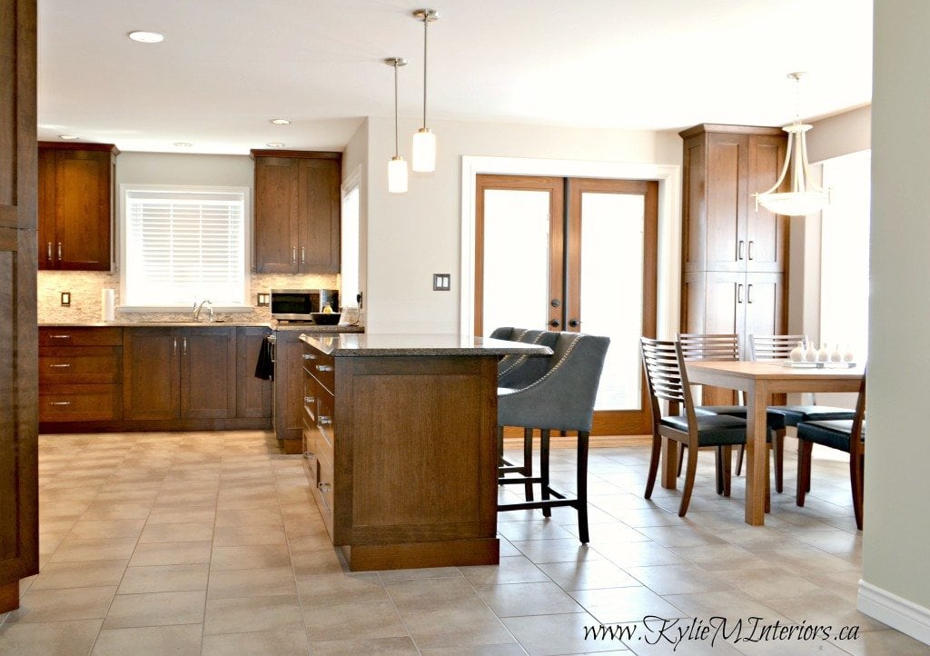 Open layout eating nook, dining area and kitchen with island in cherry or maple. Travertine tile backsplash and Benjamin Moore Abalone wall colour. Purple inspired