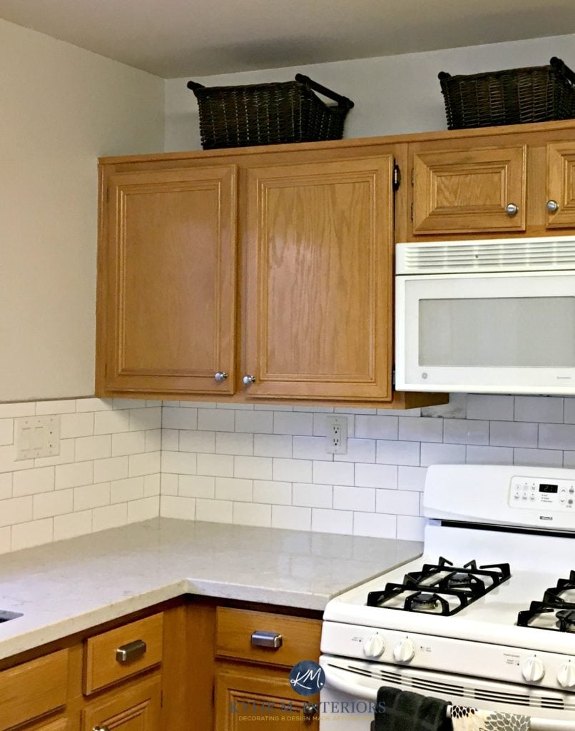 Benjamin Moore Classic Gray in a kitchen with oak wood cabinets, white subway tile and Bianco Drift quartz countertop. Kylie M E-design