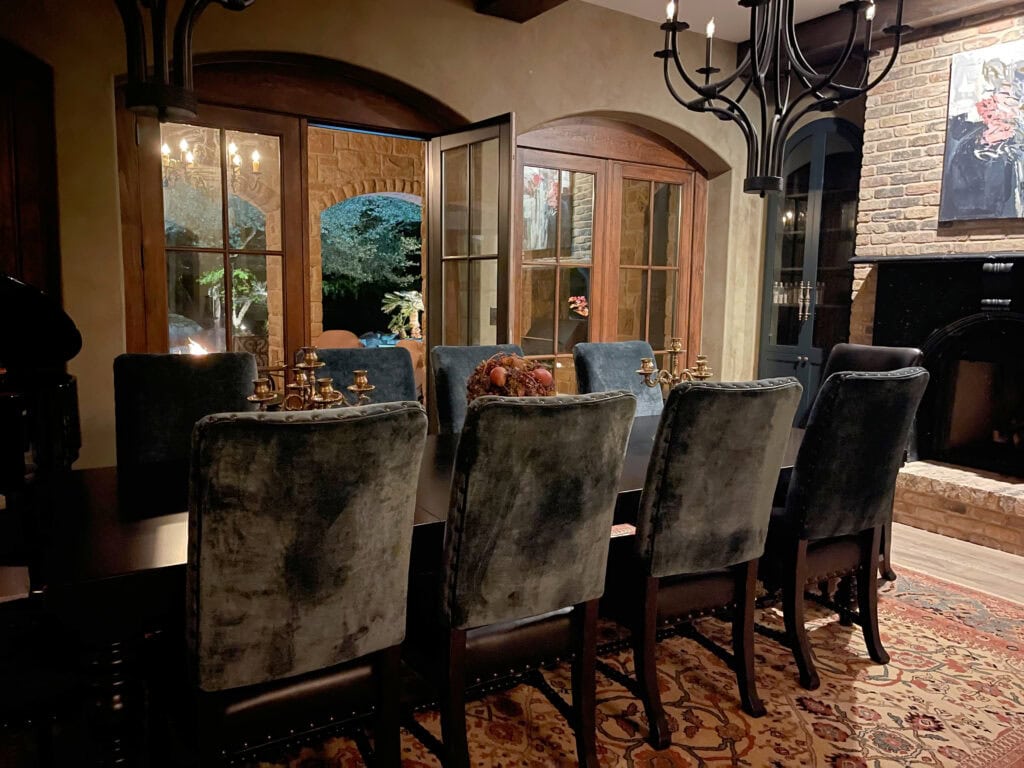Arched wood french doors. Glazed walls, modern tuscan style dining room, blue chairs, , black marble brick fireplace. Kylie M Interiors online paint color consulting