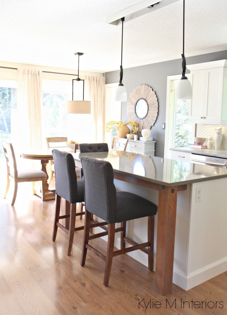 Open layout kitchen and dining room. gray quartz, rustic wood island supports. Benjamin Moore Gray on walls and Cloud White maple cabinets