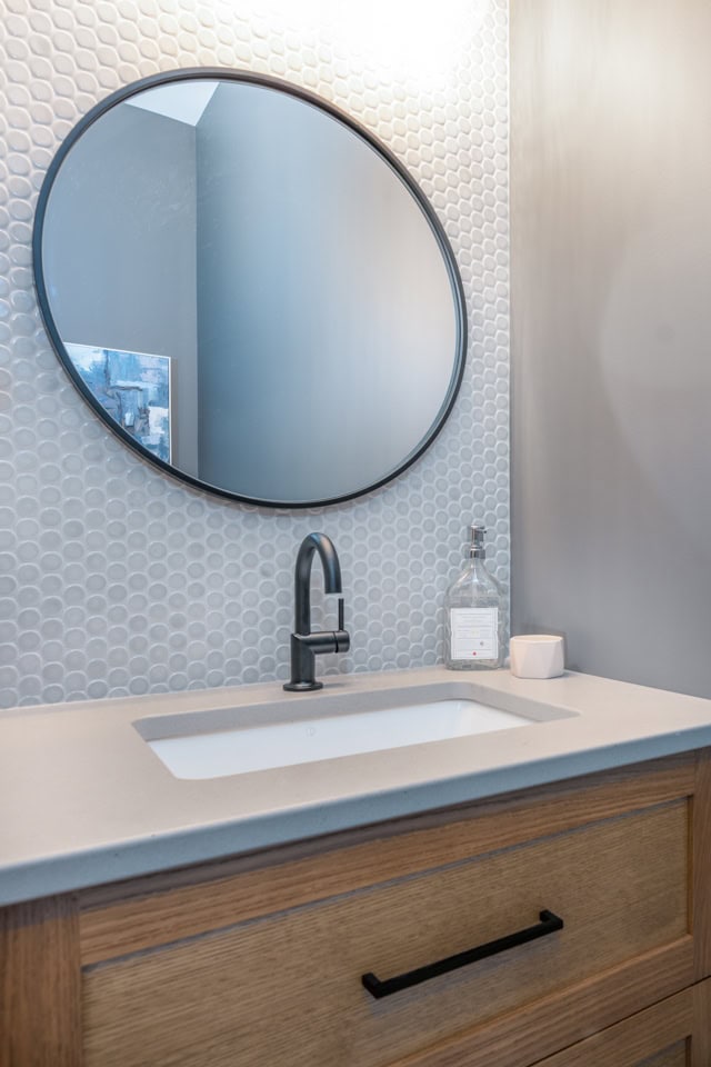Powder room small bathroom with concrete look quartz countertop, warm gray, taupe greige penny tile, white oak vanity. Kylie M Interiors Edesign, round mirror