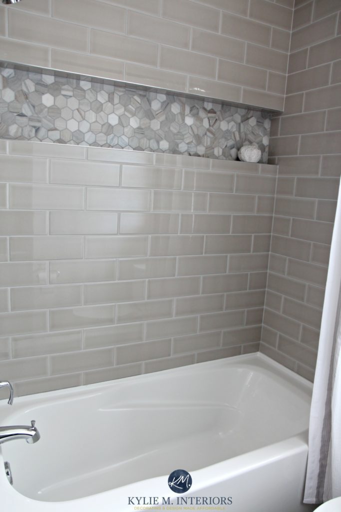 Bathroom with bathtub and gray subway tile shower surround with niche or alcove in hexagon marble tile, greige accent tile. Kylie M Interiors design