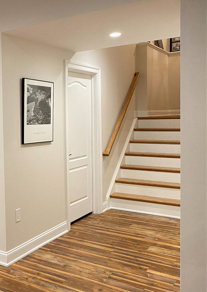 Sherwin Williams Aesthetic White, LVP wood floor, white trim, rustic wood accent behidn the TV, dark basement with no natural light.