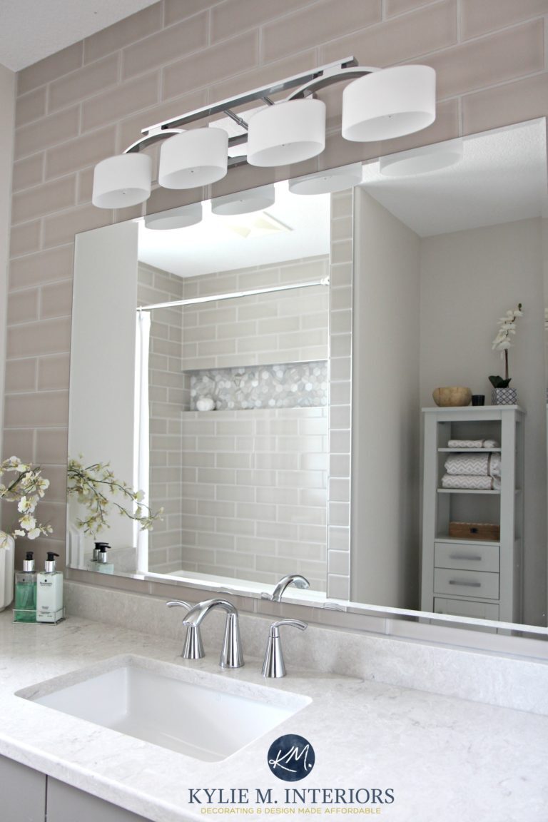 Subway tile gray wall behind vanity. Quartz countertop, Bianco Drift by Caesarstone, Moen Glyde faucet, shower surround in hexagon accent. Kylie M Interiors