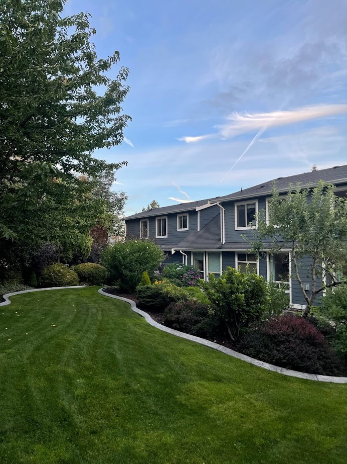 exterior concrete curbing between grass and garden beds, ideas to update yard. Kylie M. Gray blue exterior paint color, evergreens and perenials.
