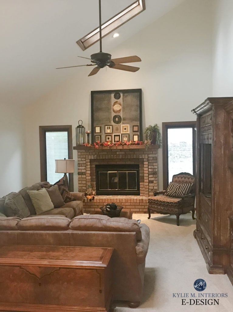 Benjamin Moore Ballet White in family room with sloped ceiling, dark wood trim, brown brick fireplace, beige carpet, dark brown furniture. Kylie M Interiors Edesign, diy update ideas