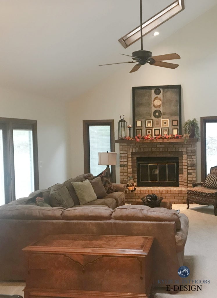 iving room with brown brick fireplace, dark wood trim, sloped ceiling, beige or tan carpet and brown furniture. Paint colour on walls is Benjamin Moore BAllet White, Kylie M Interiors Edesign