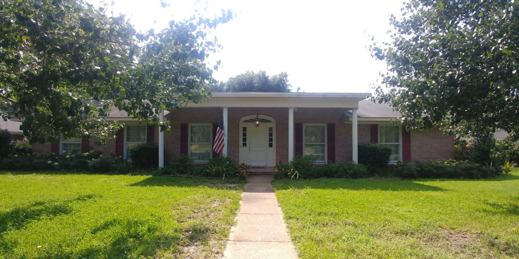 Exterior brick home BEFORE painting with ballet white, pink brick