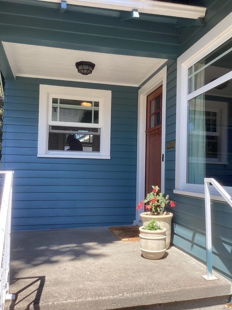 Sherwin Williams Mediterranean blue in the sun on exterior siding with Sherwin Williams Snowbound trim, concrete steps and patio and wood front door, white porch ceiling
