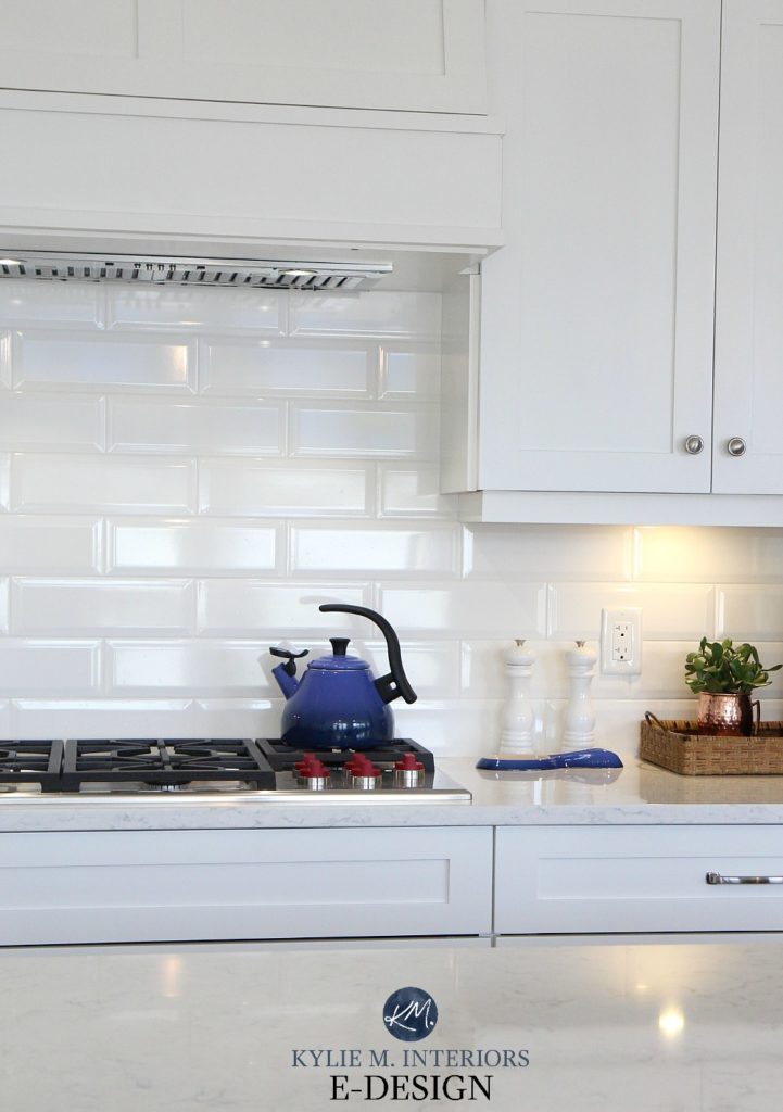 White kitchen cabinets with white bevelled subway tile backsplash, navy blue le creuset accents. Kylie M Interiors Edesign, online paint color consulting and blogger
