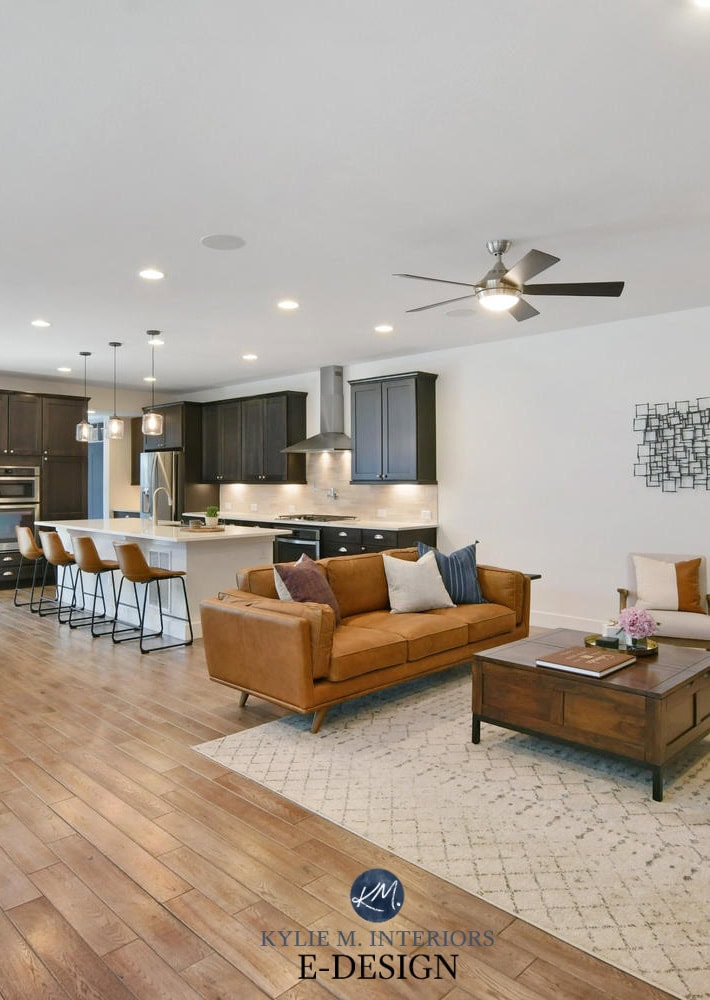 Open concept layout living, dining room and kitchen, wood tile look floor, cognac leather, Sherwin Pure White walls, dark wood cabinets. Kylie M Interiors Edesign