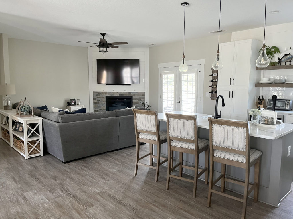 Sherwin Williams Agreeable Gray best warm grey paint colour, corner fireplace with stone and shiplap, kitchen island in Dovetail.