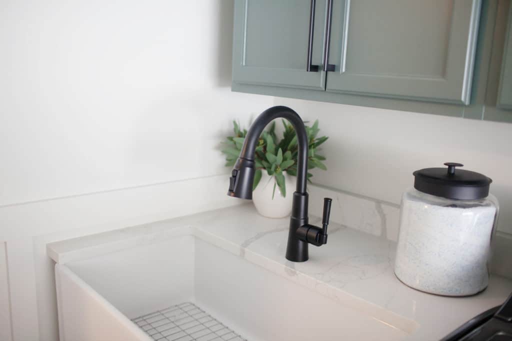 Farmhouse laundry room sink, green painted cabinets, white quartz. Kylie M Interiors Edesign, client photo, White Dove walls