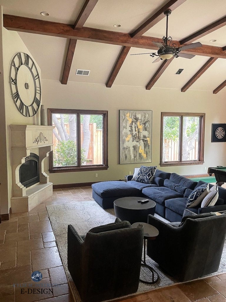 Family room with travertine tile floor, green reflection on lower walls, wood trim and beams, stone fireplace, blue sectional. Kylie M.