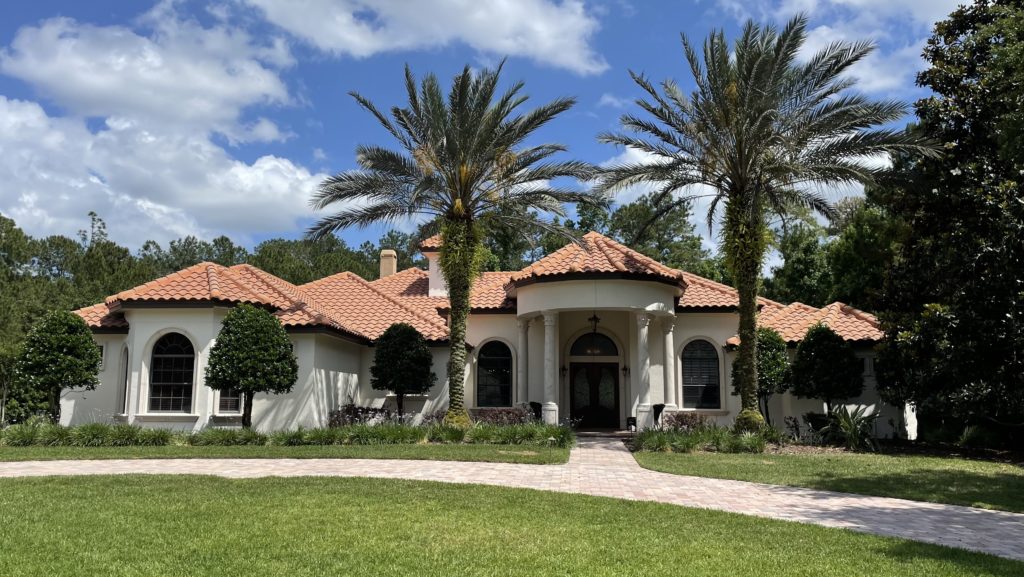 Sherwin Williams MOderate White on stucco exterior with orange red pink terra cotta tile roof, stone driveway.