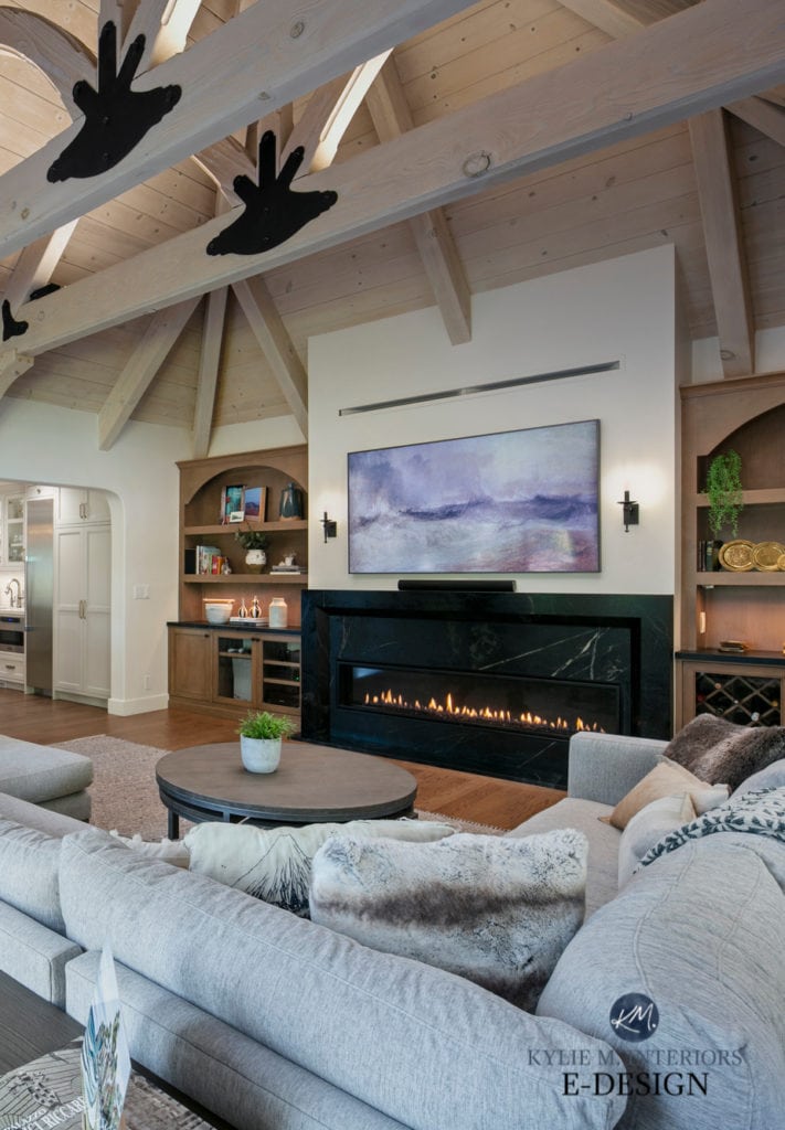 Living family room walls in Benjamin Moore White Dove, vaulted wood frame beam ceilings, fireplace with tv above, soapstone surround, wood floor. Kylie M Interiors Edesign.