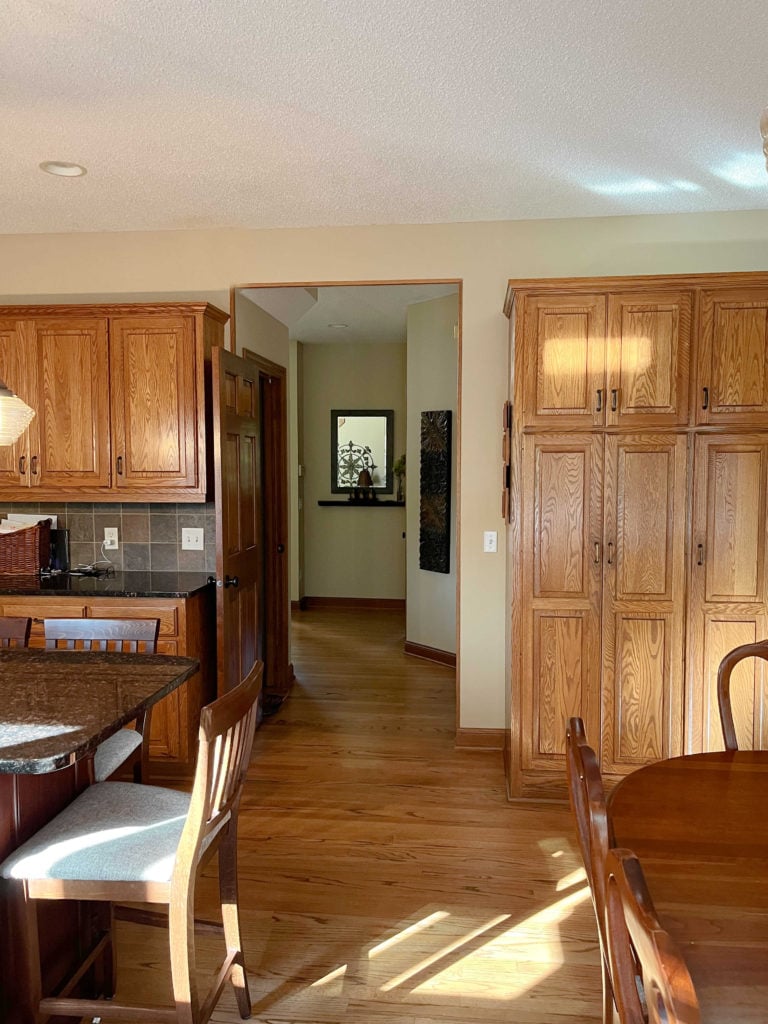 Orange toned oak cabinets, wood trim, red pink toned island oak floor, Putnam Ivory paint colour on walls.
