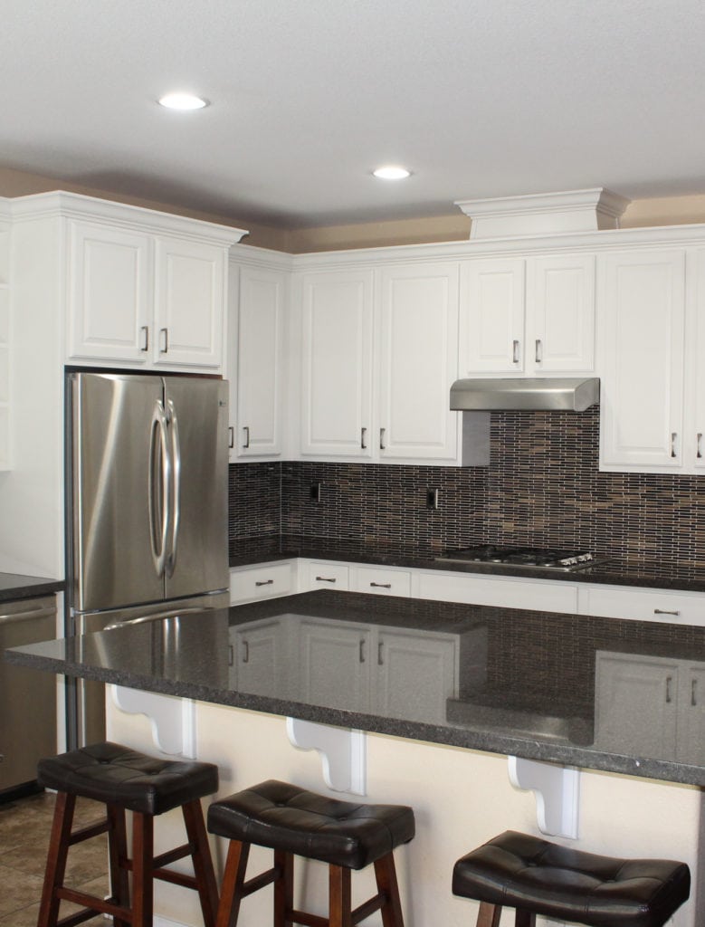 Warm white cabinets, brown black mosaic tile backsplash, black granite, beige walls. CLIENT PHOTO, Kylie M Interiors Edesign