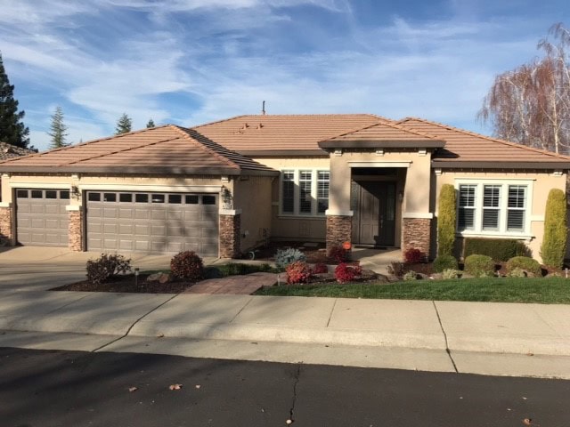 Sherwin Williams warm gray taupe on garage with warm stone extgerior, orange tile terracotta roof, beige stucco. Kylie M Interiors Edesign