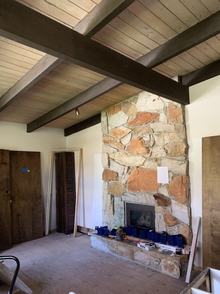 1960 orange stone fireplace, wood tongue and groove ceiling with dark wood beams