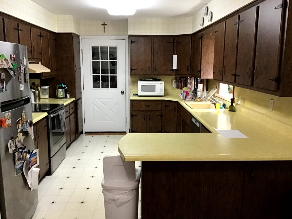 1980 kitchen before update, yellow laminate formica countertop, dark wood cabinets, black hinges, linoleum floor (1)