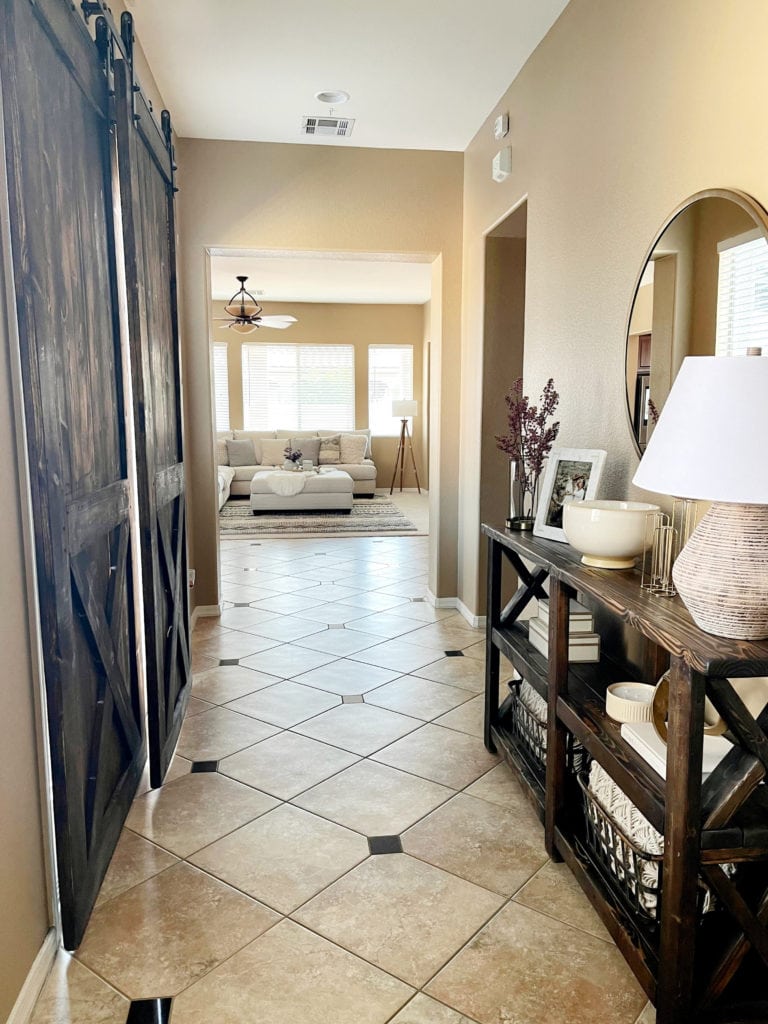 Beige tile floor with dark wood accents and warm beige or tan neutral walls. Client before photo edesign