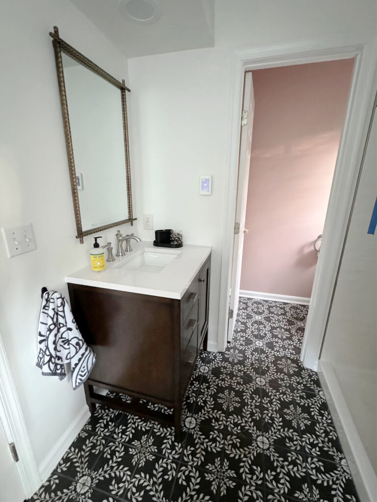 Black and white patterned tile floor, small vanity, Sherwin Williams Pure White walls, trims, Sashay Sand toilet room in bathroom.
