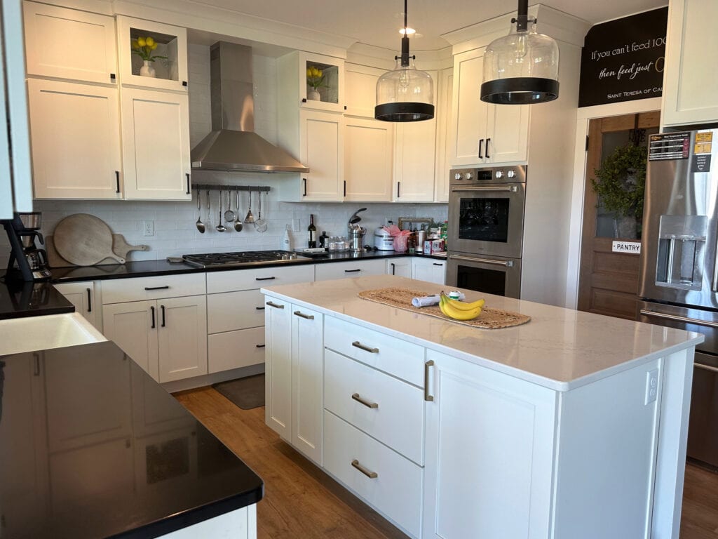 Black quartz countertop, granite look, white quartz island, Wellborn Glacier cabinets, subway tile backsplash, black hardware, stainless steel appliances