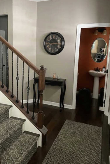 Dark entryway with Sherwin Williams Mega Greige (taupe), warm white trim, rust coloured powder room, dark wood floor. Client photo of Kylie M Interiors Edesign