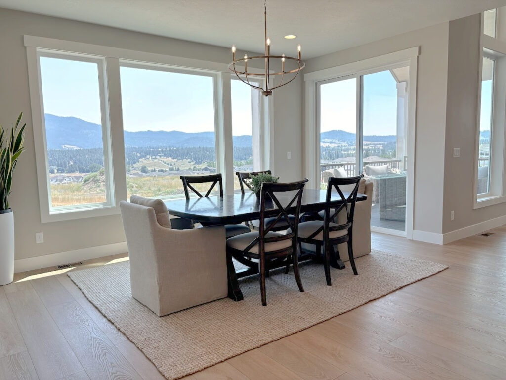 Dining room with Sherwin Williams Agreeable Gray, pure White paint colors on walls and trims, wood floor, area rug, upholsetered chair, dark wood table