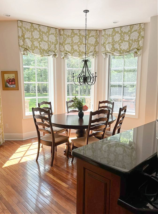 Eating nook with warm off-white walls, valance, black granite couinertop, wood floor, white trim, round table
