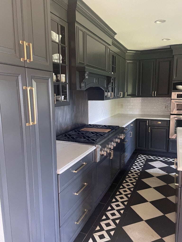 Kitchen cabinets painted Benjamin Moore Wrought Iron, soft navy blue black, white quartz countertop, subway tile backsplash, black and white checkerboard pattern floor, gold hardware