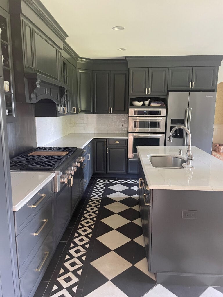 Kitchen with white and black checkerboard tile floor, wood cabinets painted BEnjamin Moore Wrought Iron, soft navy blue black, subway tile, white quartz countertop, stainless steel. Update idea