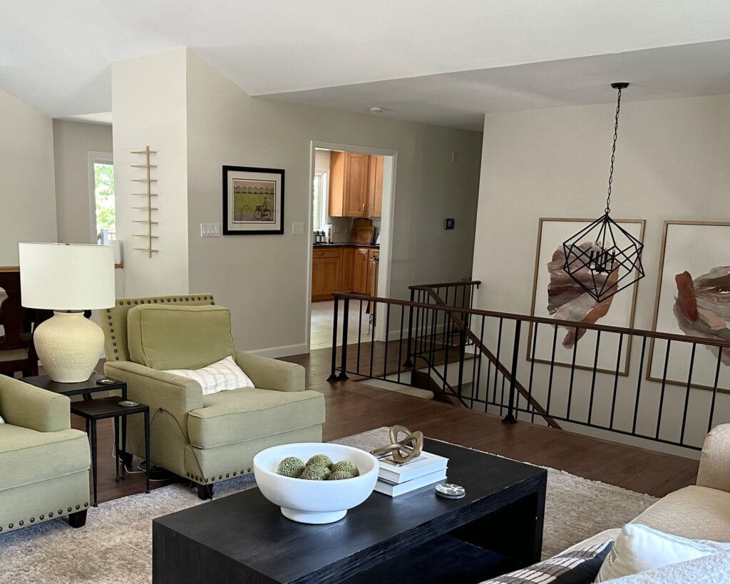 Metal stair railing in split level home with green accent chairs in living room, Sherwin Williams White Duck paint color on walls