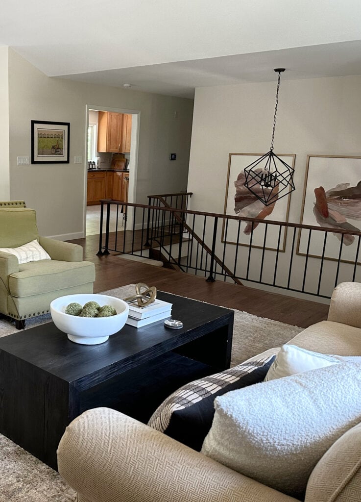 Metal stair railing, split level home, open concept, Sherwin Williams White Duck paint color on walls, green accent chair, coffee table with decor