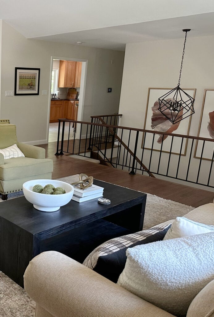 Open concept, split level home with metal stair railing,wood floor, art and home decor, dark wood coffee table, green accent, Sherwin Williams White Duck