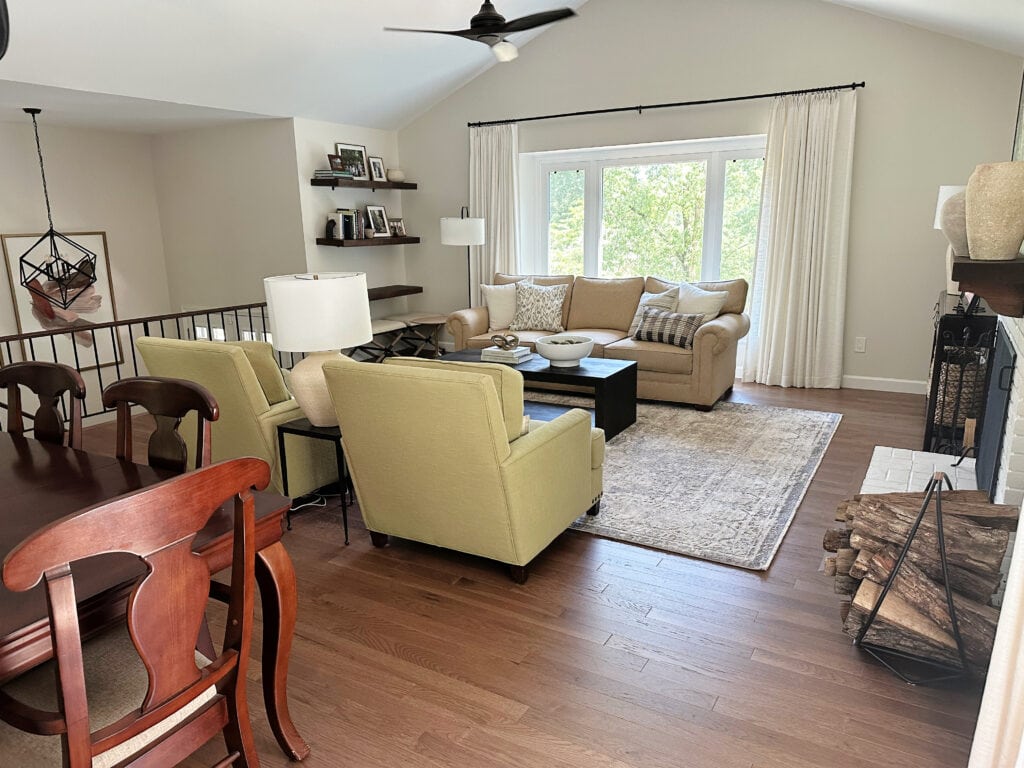 Open concept split level home, wood floor, green accent chairs, Sherwin Williams White Duck paint color, off-white on walls, vaulted ceiling with fan