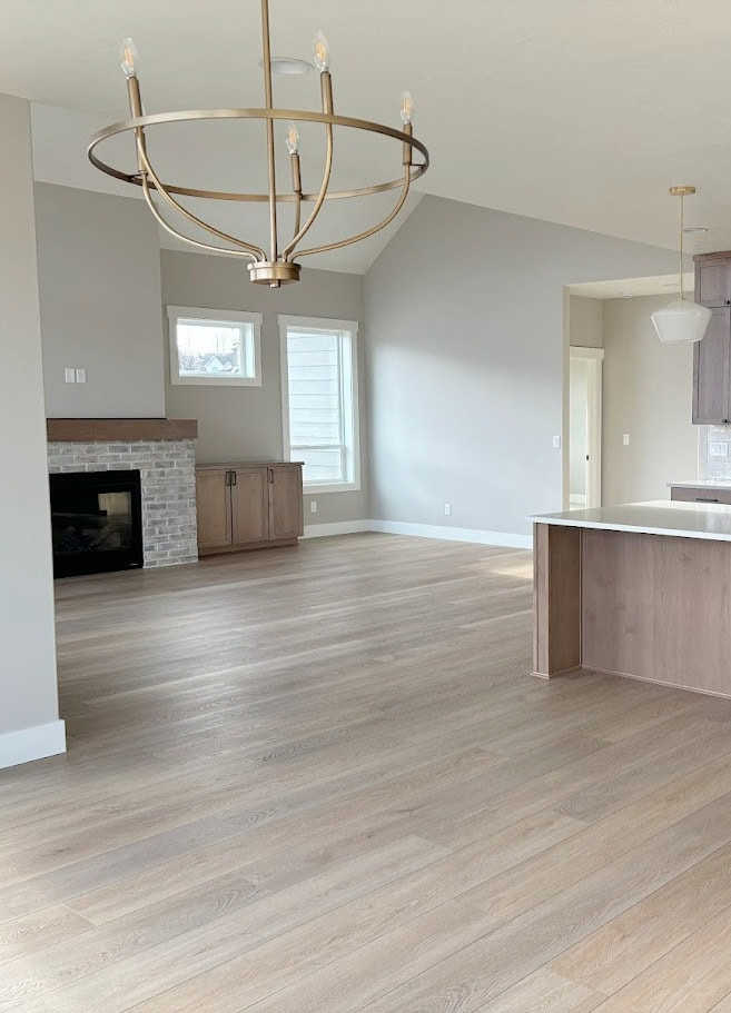 Open concept living room, dining room, kitchen, graywash wood floor, wood cabinets and built-ins, brick fireplace, mantel, Sherwin Williams Agreeable GRay, pure White, gold chandelier light