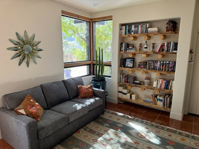 Rustic, southwestern style, desert den with wood shelves, gray sectional, wood trim, terra cotta look tile floor, Sherwin Williams beige on walls
