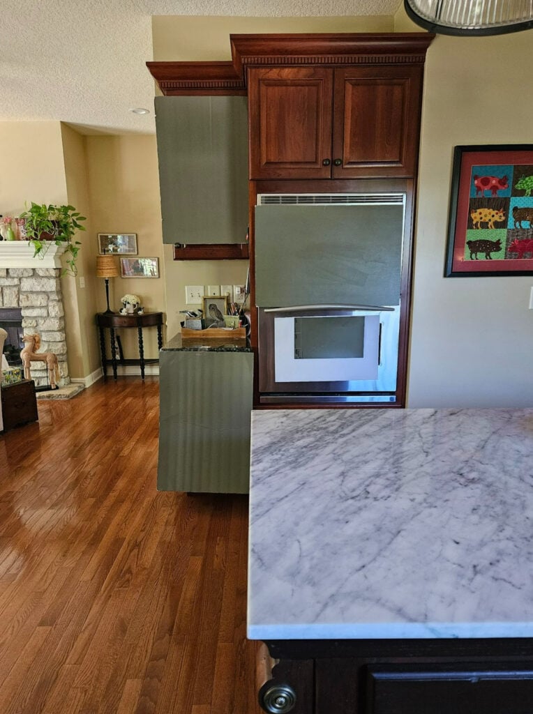 Sherwin Williams Cocoon, dark green paint color for painting dark red stained wood cabinets, oak floor, marble island countertops