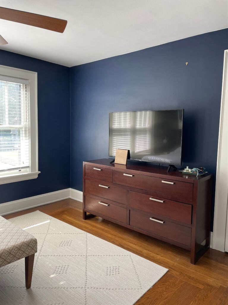Sherwin Williams Naval, dark navy blue paint color, orange oak wood floor, Alabaster trim in bedroom