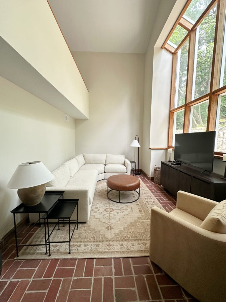Sherwin Williams White Duck, red pink terra cotta color brick floors, high ceiling, wood window trims, cream sectional.