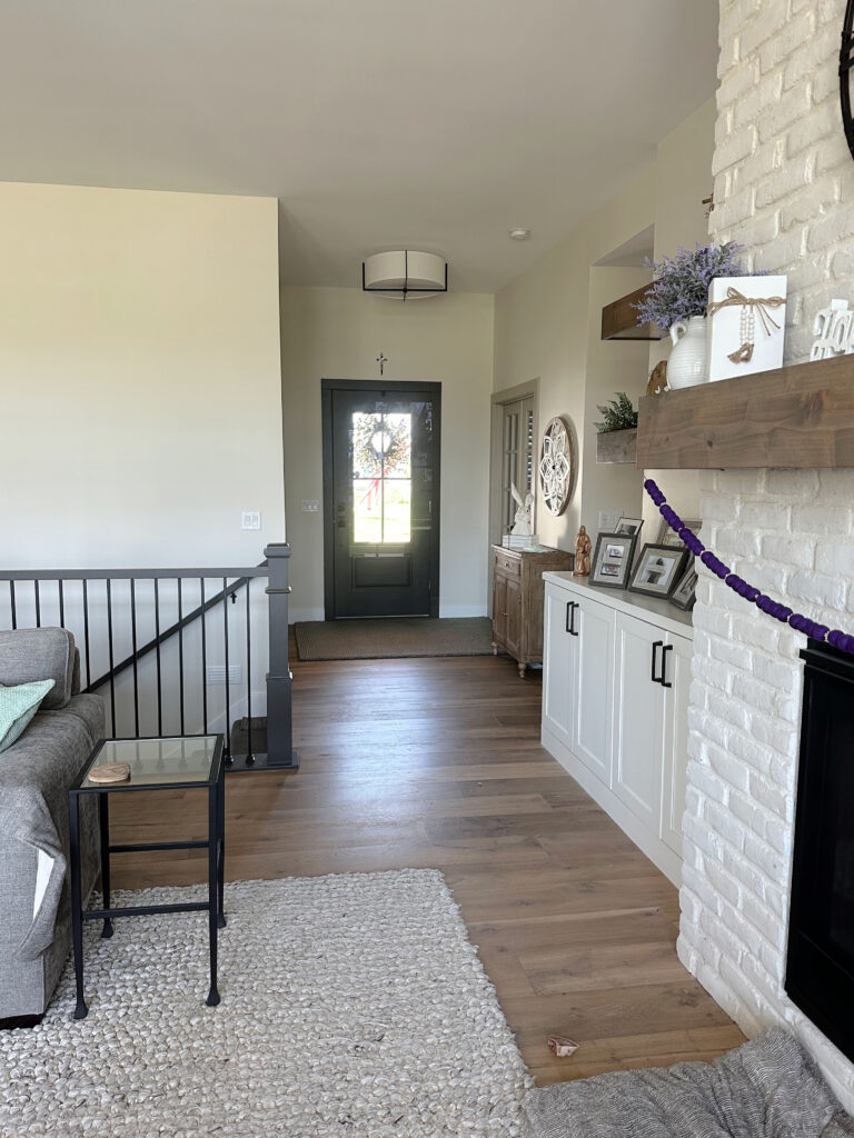 Sherwin Williams White Duck warm neutral on walls, Urbane Bronze painted stair railing and inside front door, paitned brick and wood floor. Kylie M.