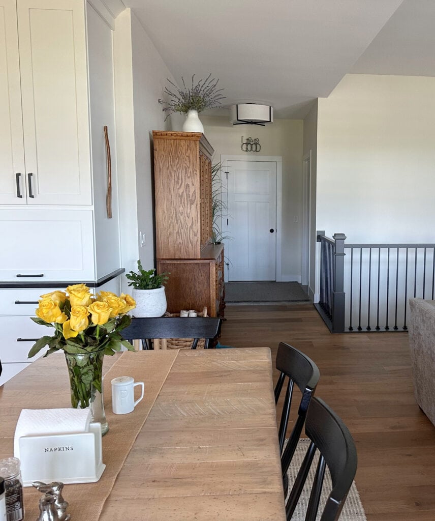 Sherwin Williams White Duck warm off white paint on walls, Urbane Bronze painted stair railing, black spindles, wood floor, taupe sofa. Pure White trim