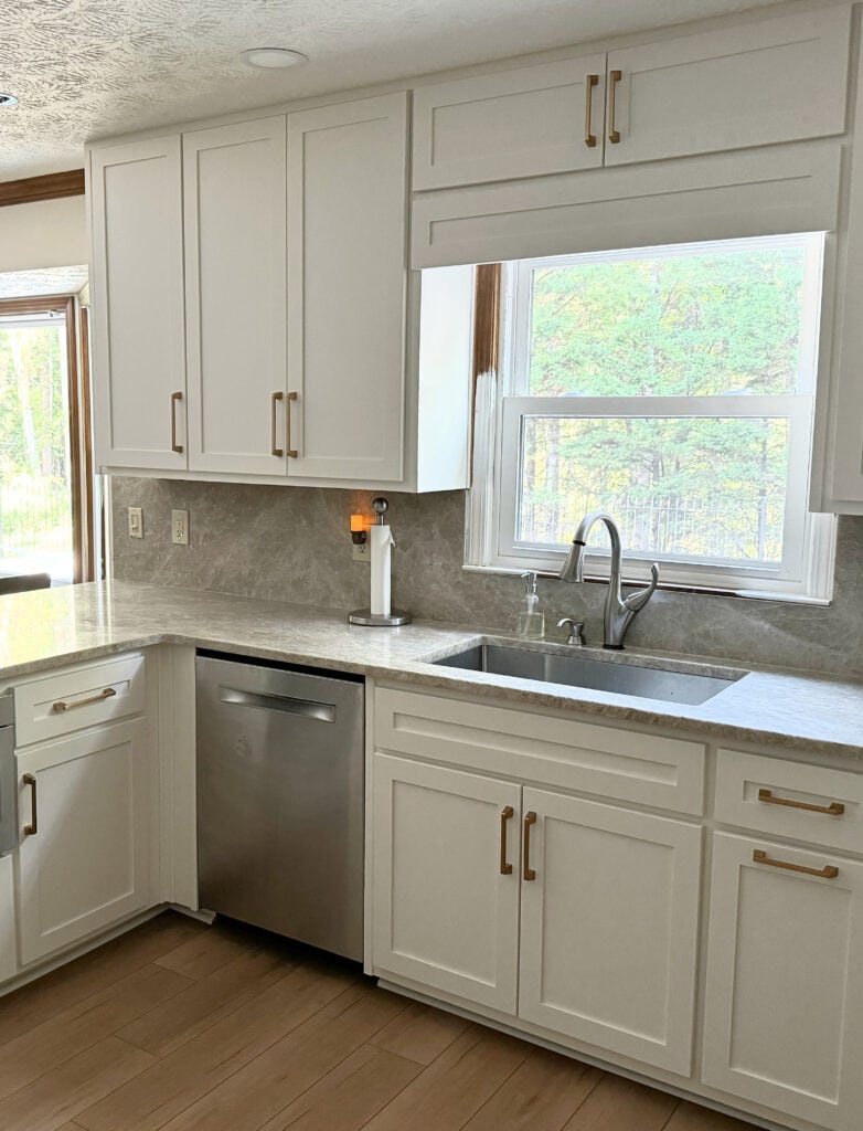 Taj Mahal quartzite countertop with Calypso Oak from Coretec flooring, gold antique brass cabinet hardware, countersplash, countertop on the backsplash, stainless steel appliances (1)