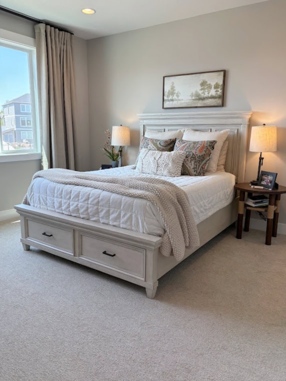 bedroom with warm gray, taupe carpet, wood bed frame, side tables, room decor, linens, Sherwin Williams Agreeable Gray walls and pure white trim paint color