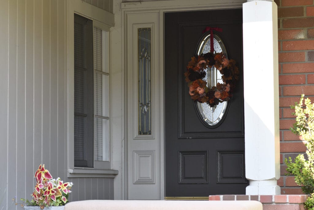 brick exterior with Sherwin Williams Jogging Path best greige paint color on siding and matching trim, dark black gray front door