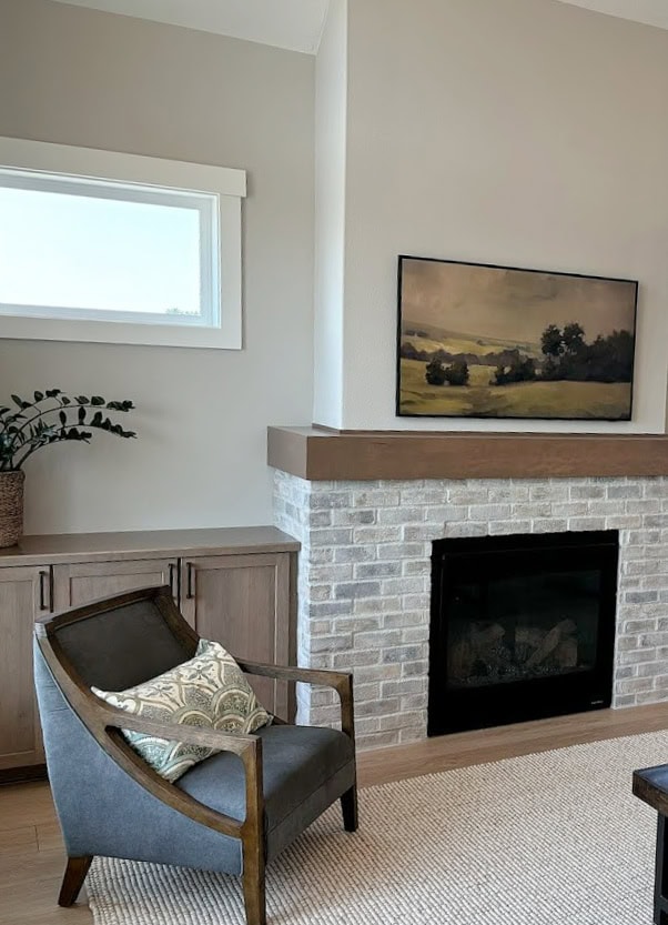 brick fireplace, wood mantel, wood cabinet built ins in living room, area rug, accent chair, Sherwin Williams Agreeable Gray wall paint color, Pure White trim