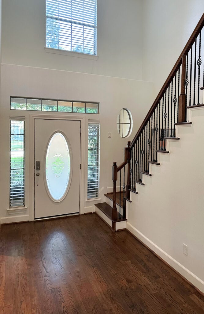 entryway or foyer with dark wood stained oak floor, stairs, metal railing, Sherwin Williams Dover White warm creamy or creamy white walls.