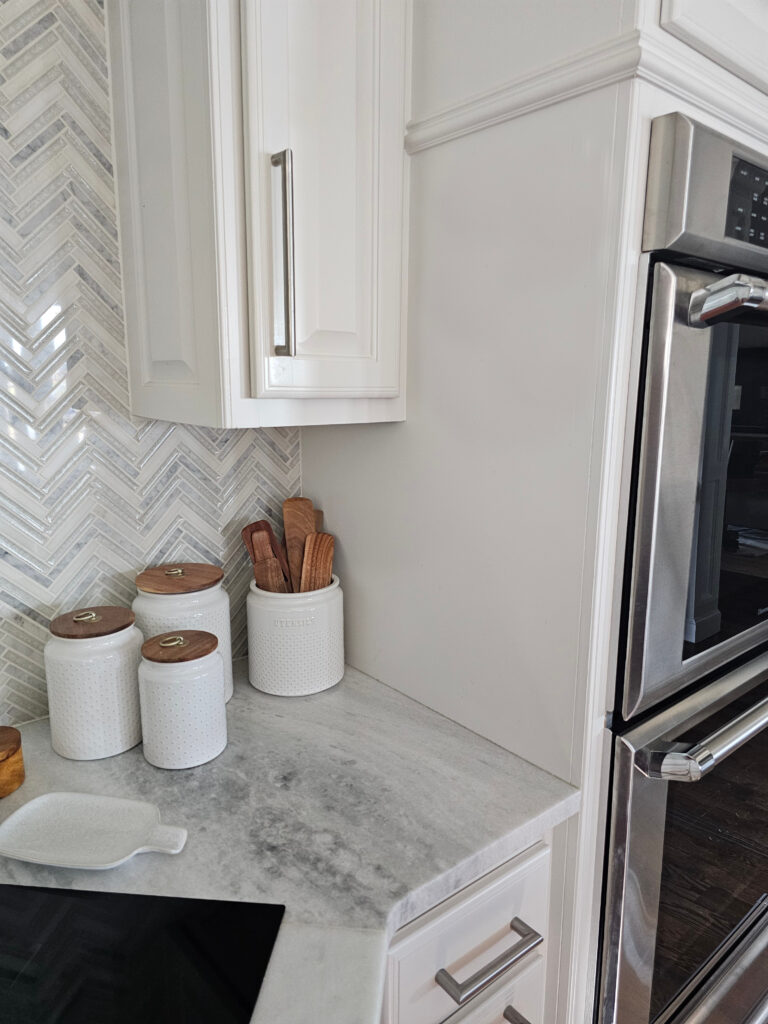 kitchen cabinets painted sherwin williams zurich white with quartzite countertops, herringbone backsplash, off-white.